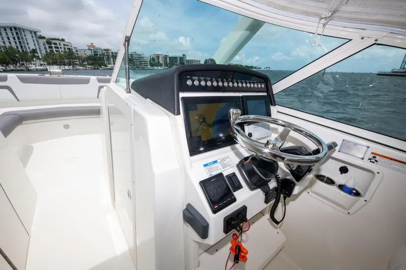 Slide: The Image of 2019 World Cat 296DC boat helm with steering wheel and navigation controls. - 35