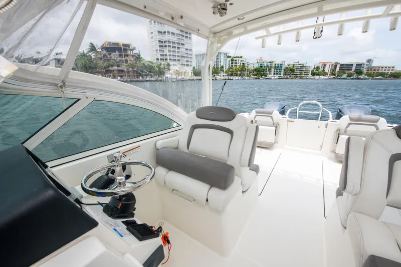 Slide: The Image of 2019 World Cat 296DC boat interior with steering wheel and seating, overlooking waterfront buildings. - 41