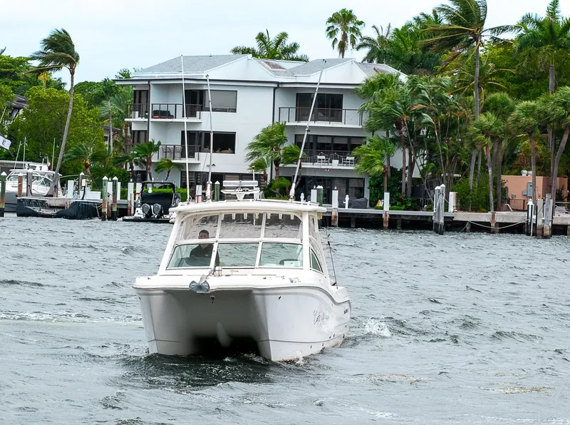 Slide: The Image of 2019 World Cat 296DC boat cruising near waterfront homes with palm trees. - 48