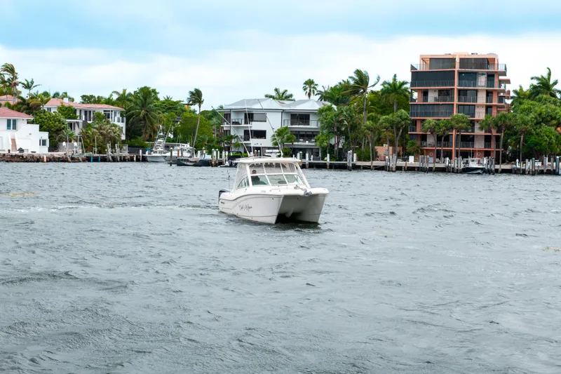 Slide: The Image of 2019 World Cat 296DC boat cruising on a scenic waterfront with modern homes. - 5