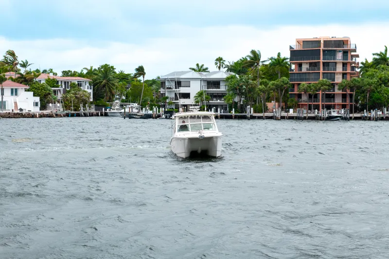 Slide: The Image of 2019 World Cat 296DC boat cruising near waterfront homes on a cloudy day. - 6