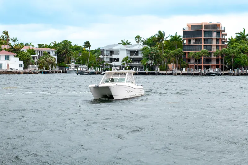 Slide: The Image of 2019 World Cat 296DC boat cruising on a scenic waterfront with modern homes. - 8