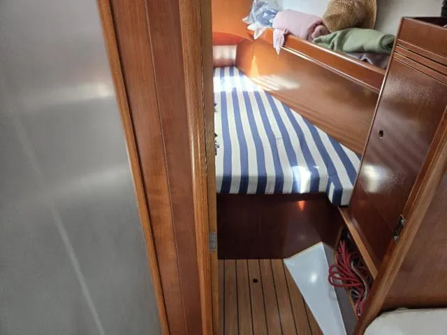 Slide: The Image of Cabin interior of 2002 Beneteau First 36.7 with striped bedding and wooden finish. - 6