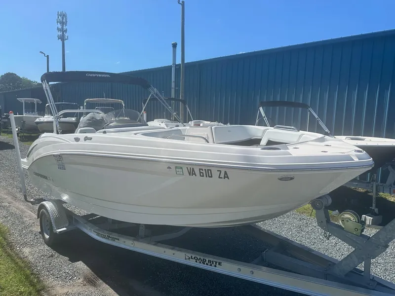Slide: The Image of 2018 Chaparral 191 Suncoast boat on trailer, parked outdoors near blue building. - 2