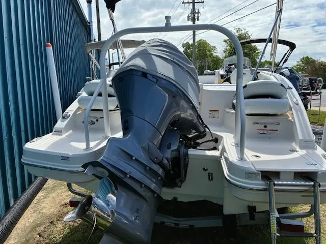 Slide: The Image of 2018 Chaparral 191 Suncoast boat with outboard motor, docked near a blue building. - 5