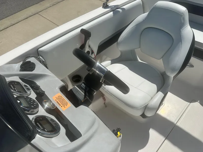 Slide: The Image of 2018 Chaparral 191 Suncoast boat cockpit with steering wheel and white captain's chair. - 9