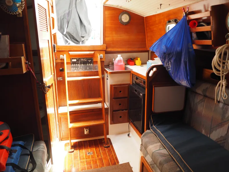 Slide: The Image of Interior of a 1996 Com-Pac 27-2 sailboat with wooden finishes and compact kitchen area. - 16