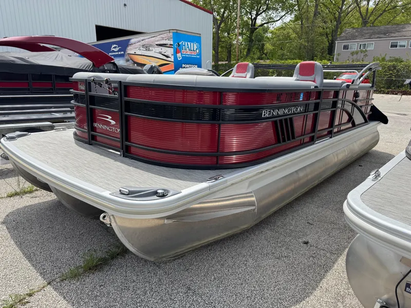 Slide: The Image of 2022 Bennington 22 LSR pontoon boat with red and black accents, parked outdoors. - 11