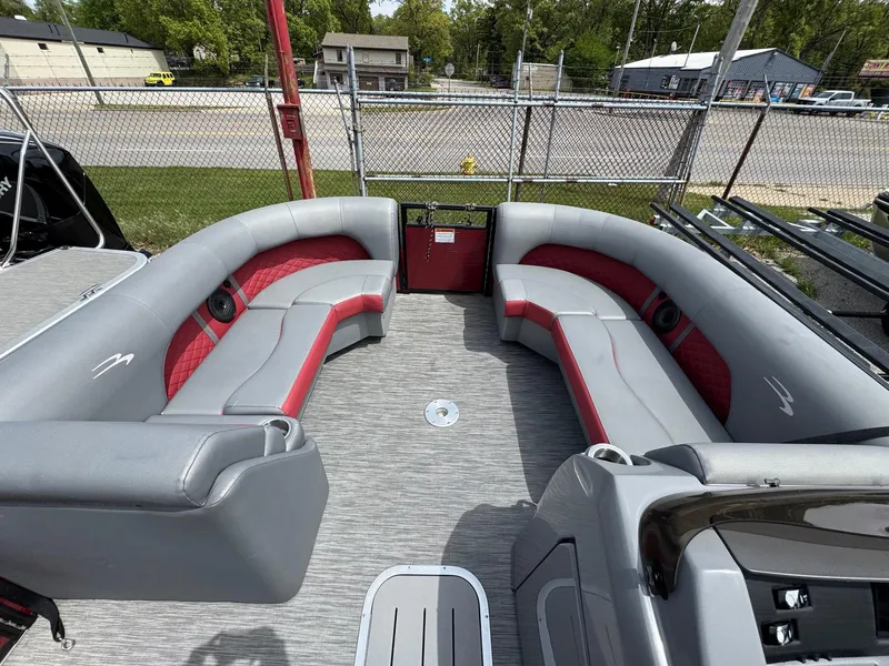 Slide: The Image of 2022 Bennington 22 LSR boat interior with gray and red seating, docked outdoors. - 4
