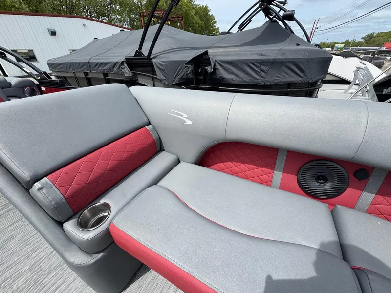Slide: The Image of 2022 Bennington 22 LSR boat interior with red and gray seating, cup holder, and speaker. - 7