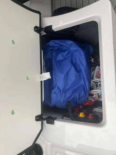 Slide: The Image of Storage compartment of 2024 Yamaha Boats 252 S with blue cover and accessories. - 23