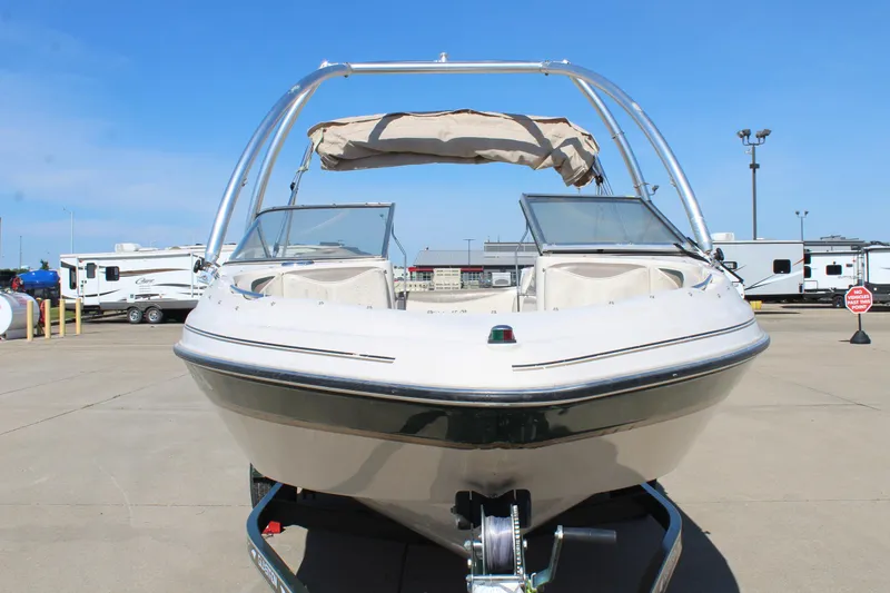 Slide: The Image of 2001 Glastron GX 185 boat on trailer, parked in a lot under clear blue sky. - 2