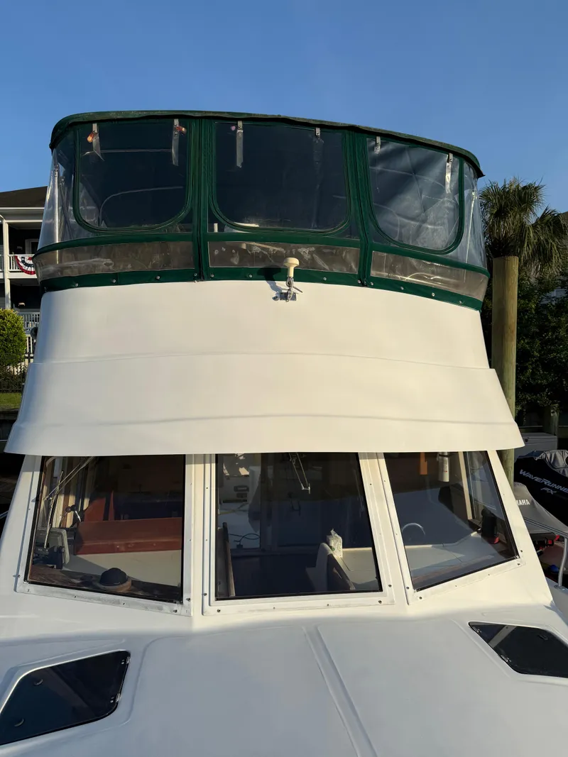 Slide: The Image of 2000 Mainship 390 Trawler with green canopy, docked under clear blue sky. - 19