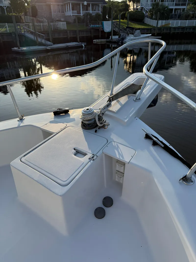 Slide: The Image of 2000 Mainship 390 Trawler bow with railing, winch, and storage compartment at sunset. - 20