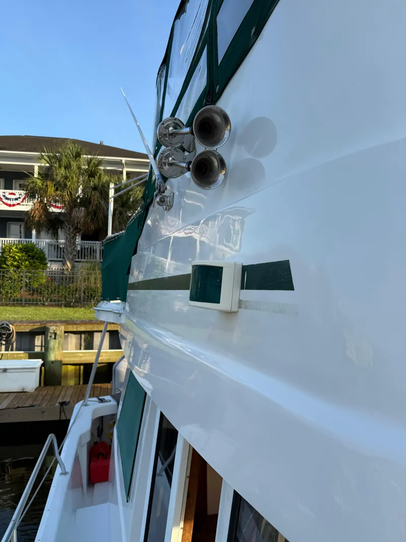 Slide: The Image of 2000 Mainship 390 Trawler docked, showcasing sleek white exterior and green accents. - 24