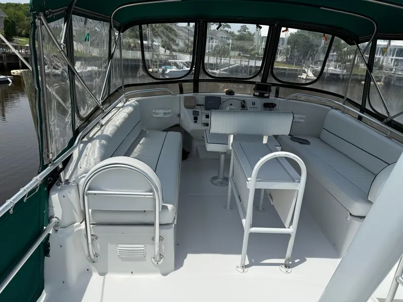 Slide: The Image of 2000 Mainship 390 Trawler interior with seating and helm, featuring green canopy. - 3