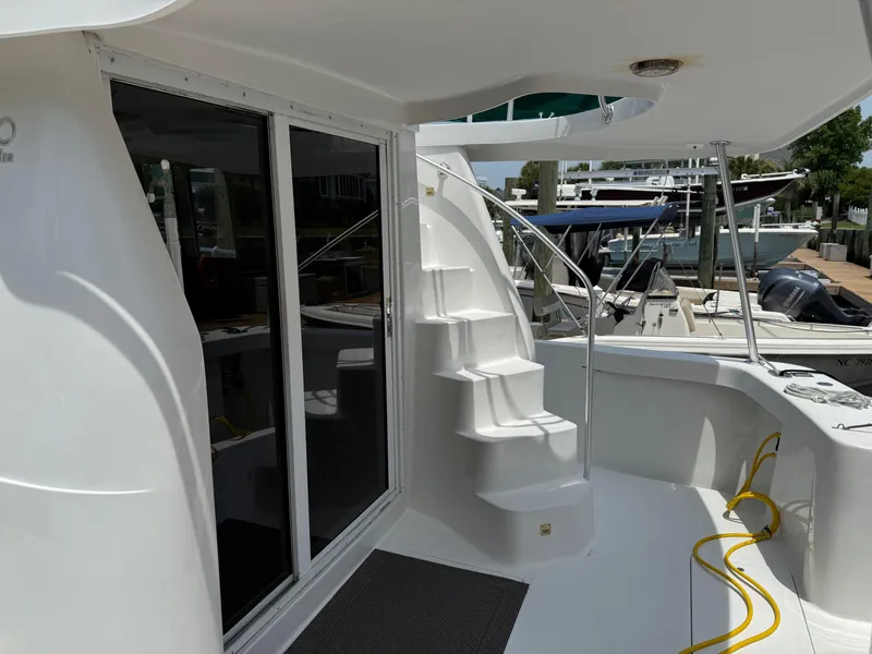 Slide: The Image of 2000 Mainship 390 Trawler deck with stairs, sliding doors, and marina view. - 5