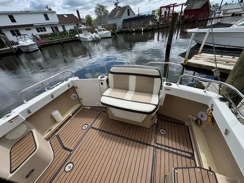 Slide: The Image of 2016 Cutwater C-26 boat with spacious deck and seating, docked by waterfront homes. - 12