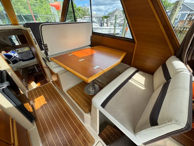 Slide: The Image of 2016 Cutwater C-26 interior with wood accents, dining table, and cushioned seating. - 21