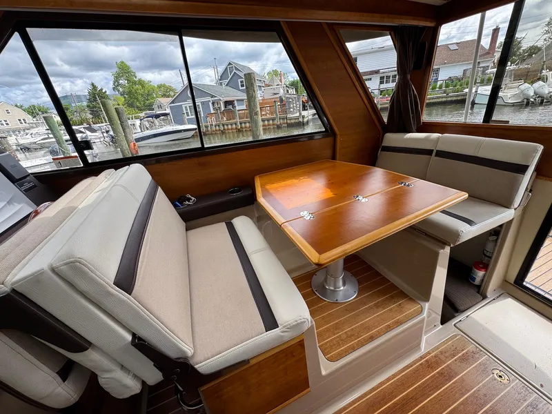 Slide: The Image of Interior of a 2016 Cutwater C-26 boat with a wooden table and cushioned seating. - 28