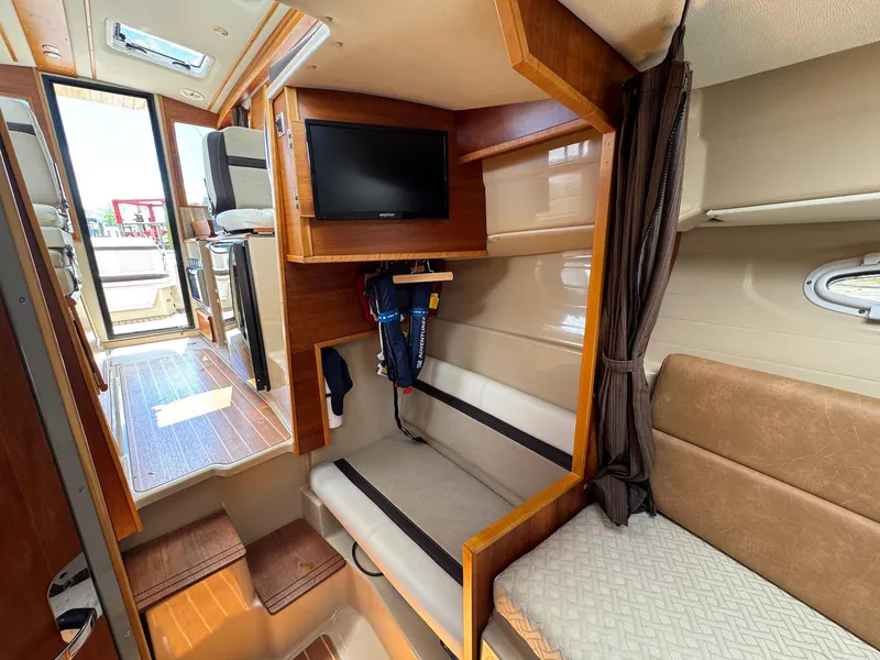 Slide: The Image of Interior of a 2016 Cutwater C-26 boat, featuring seating, TV, and wooden finishes. - 33