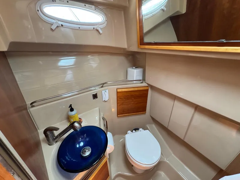 Slide: The Image of 2016 Cutwater C-26 boat bathroom with blue sink, toilet, and porthole window. - 35