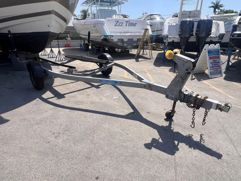 The Image of Boat trailer model 19, 2022, parked in a marina with boats in the background. - 1