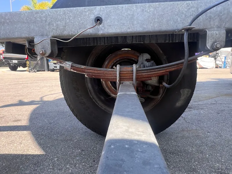 Slide: The Image of Close-up of a 2022 Trailer 19 wheel and suspension system in a parking lot. - 11