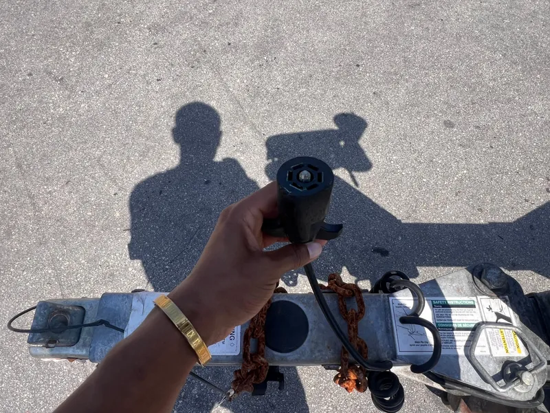 Slide: The Image of Hand holding trailer connector, shadow on pavement, 2022 Trailer model 19. - 8