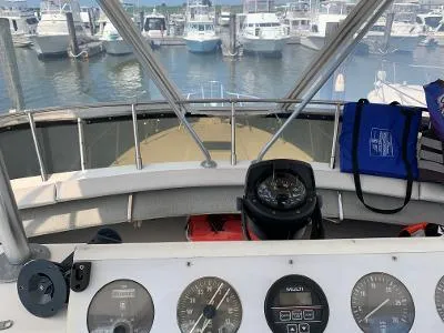 Slide: The Image of 1989 Trojan 12 Meter Convertible boat dashboard with gauges, compass, and marina view. - 16