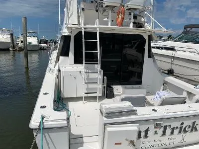 Slide: The Image of 1989 Trojan 12 Meter Convertible yacht docked at marina, rear view with ladder and seating. - 5