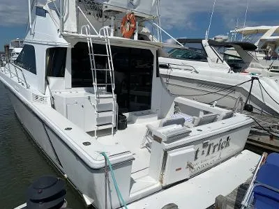 Slide: The Image of 1989 Trojan 12 Meter Convertible yacht docked at marina, featuring spacious deck and ladder. - 7