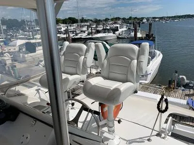 Slide: The Image of 1989 Trojan 12 Meter Convertible yacht with white captain chairs at a marina. - 22