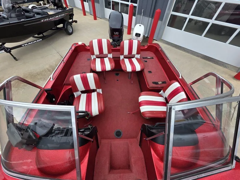 Slide: The Image of Red 1997 Ranger 692 boat with striped seats and windshield, parked near a garage. - 14