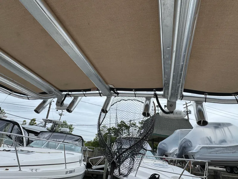 Slide: The Image of Tidewater 198 CC Adventure 2020 boat with fishing rod holders and net, docked alongside other boats. - 11