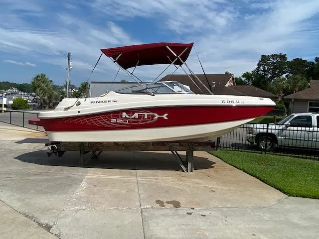 Slide: The Image of 2013 Rinker Captiva 220 MTX boat with red canopy on a driveway. - 1