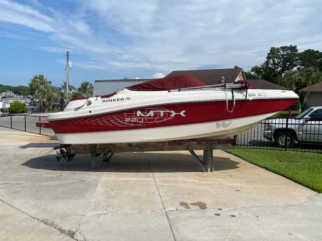 Slide: The Image of 2013 Rinker Captiva 220 MTX boat on trailer, red and white design, parked outdoors. - 10