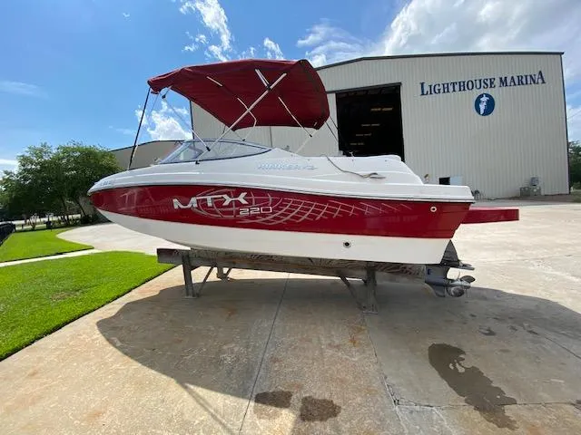 Slide: The Image of 2013 Rinker Captiva 220 MTX boat at Lighthouse Marina, featuring red and white design. - 2