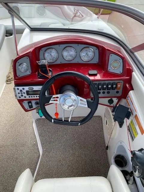 Slide: The Image of 2013 Rinker Captiva 220 MTX boat dashboard with red accents and steering wheel. - 4