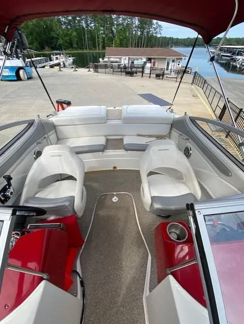 Slide: The Image of 2013 Rinker Captiva 220 MTX boat interior with red accents, docked at a marina. - 5