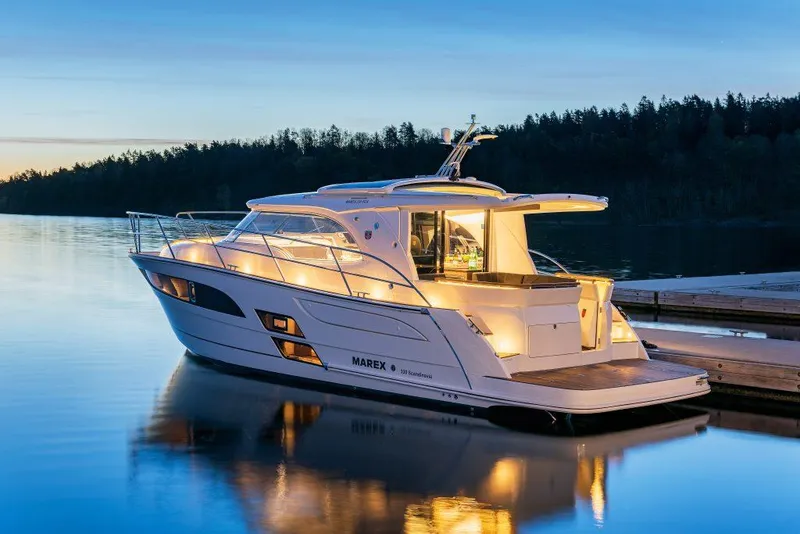 Slide: The Image of 2025 Marex 330 Scandinavia yacht illuminated at sunset on calm water. - 14