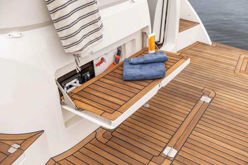 Slide: The Image of 2025 Marex 330 Scandinavia boat deck with storage compartment, towels, and striped cloth. - 24