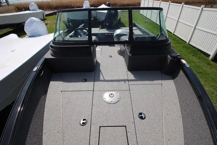 Slide: The Image of 2025 Lund 1875 Impact XS Sport boat, spacious deck, windshield, outdoor setting. - 8
