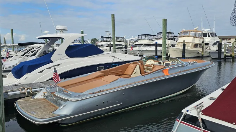 Slide: The Image of 2013 Chris-Craft Launch 32 boat docked in a marina, surrounded by other vessels. - 0