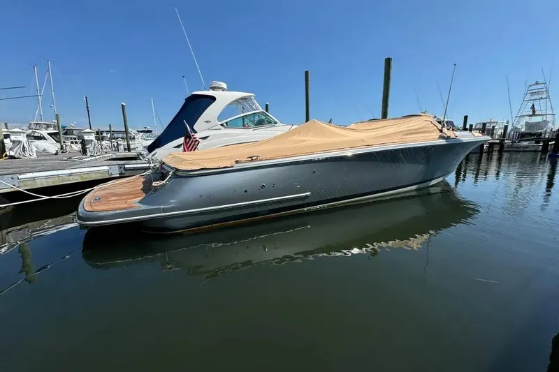 Slide: The Image of 2013 Chris-Craft Launch 32 boat docked, covered, in a marina under clear blue sky. - 24
