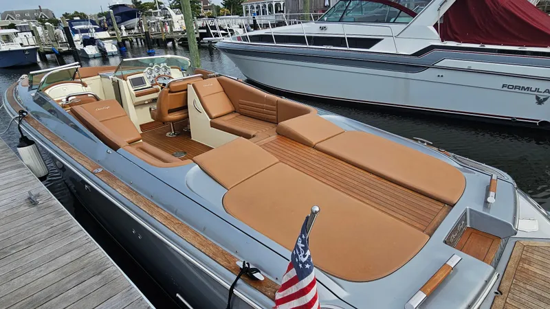 Slide: The Image of 2013 Chris-Craft Launch 32 boat docked, featuring tan seating and American flag. - 4