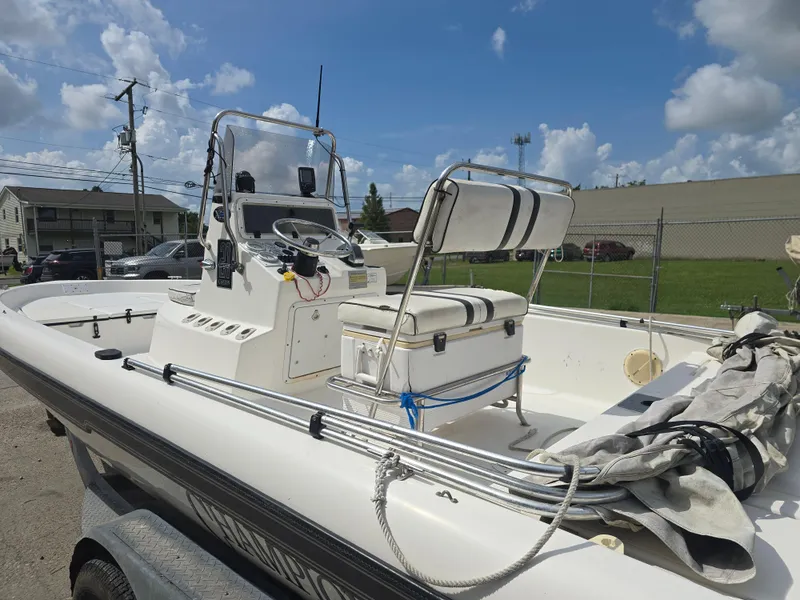 Slide: The Image of 2000 Champion 21 Bay Champ boat with center console and seating, parked outdoors. - 10