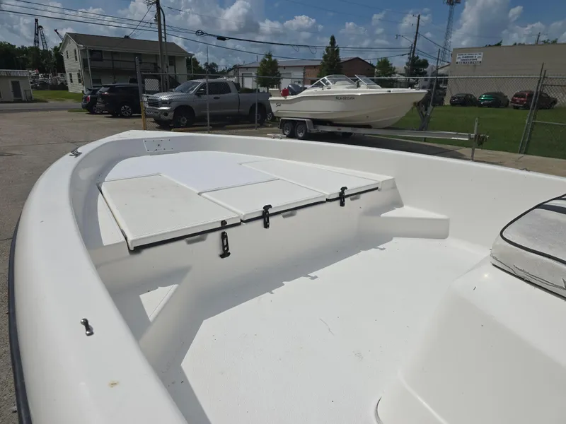 Slide: The Image of 2000 Champion 21 Bay Champ boat, white interior, parked outdoors on a sunny day. - 11