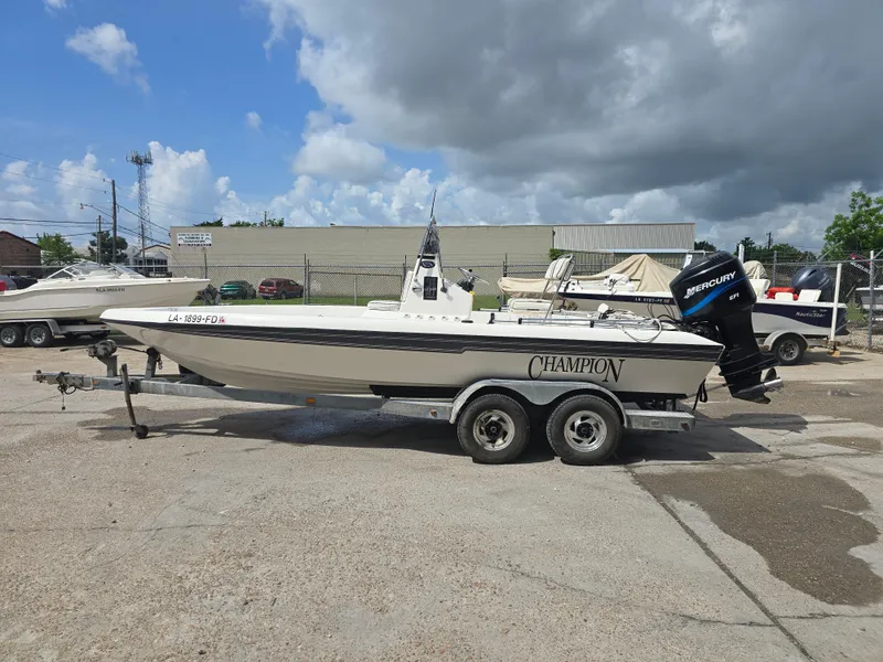 Slide: The Image of 2000 Champion 21 Bay Champ boat on trailer, parked outdoors under cloudy sky. - 3