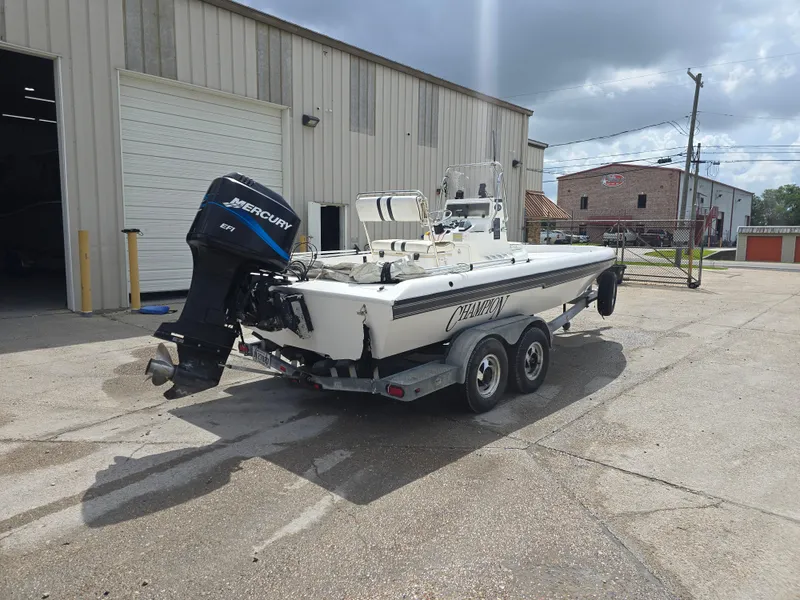 Slide: The Image of 2000 Champion 21 Bay Champ boat on trailer with Mercury outboard motor, parked outside a warehouse. - 6